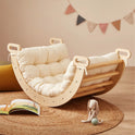 Curved wooden rocker featuring a cream-colored Thick Padded Play Cushion, resting on a round woven rug and a padded play mat.
