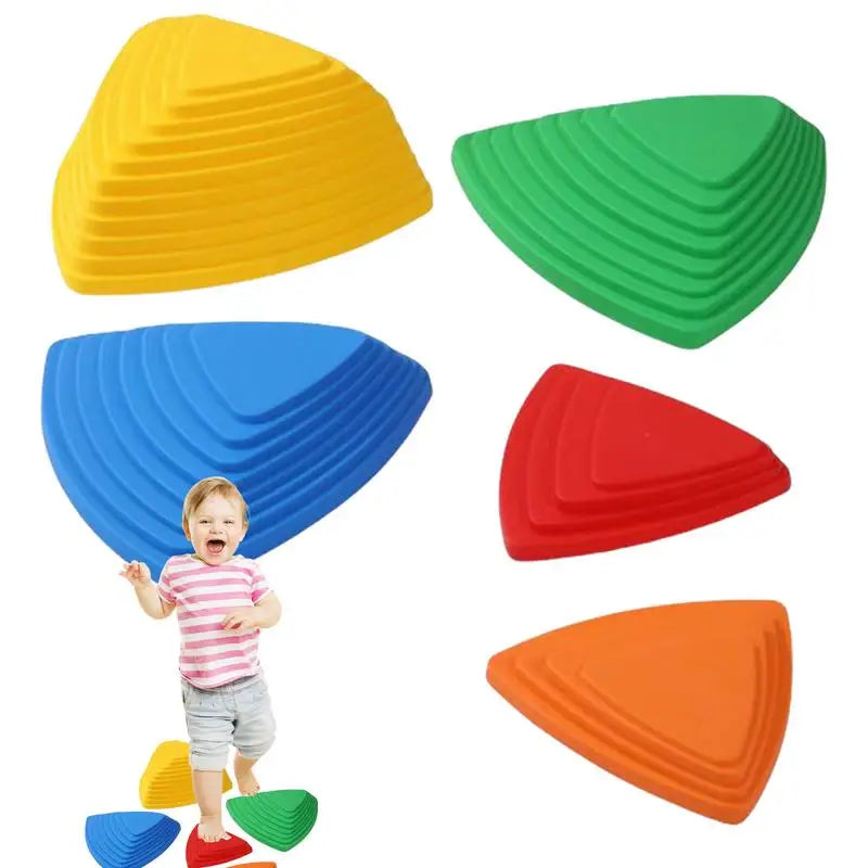 A child wearing a striped shirt and shorts smiles while standing on Kids Balance River Stones in yellow, green, blue, red, and orange. These non-slip sensory toys are ideal for imaginative obstacle courses promoting fun play and skill development.