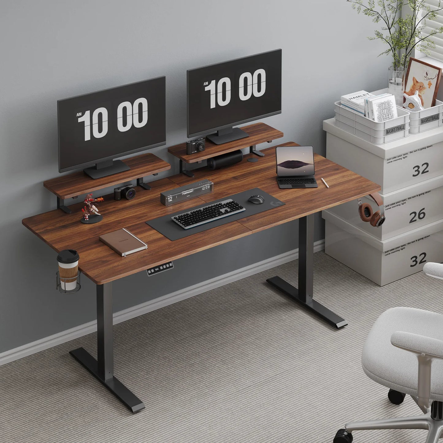 A modern home office features the Standing Desk w/ 2 Adjustable Monitor Shelves Electric Stand Up Desk (63 Walnut) with dual monitors, keyboard, mouse, camera, headphones, cup holder, side drawers, and an ergonomic chair.