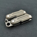 A compact Fidget Magnetic Coin EDC Decompression Toy with a metallic gray finish and visible screws, showcasing its multifunctional crowbar slider spinner design, rests on a dark textured surface.