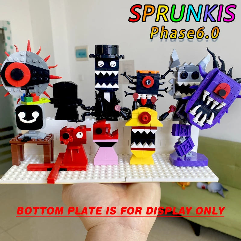 A hand displays the white New Moc Incredibox Sprunki Building Blocks Set, featuring colorful horror anime monster figures with sharp teeth and big eyes, perfect as a music game toy or gift for birthdays and Christmas. Blurred living room background.