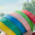 A hand holds five rolls of Sticky Toys For Kids Multifunctional Sticky Ball Tapes in yellow, green, blue, pink, and red—great for travel crafts or stress relief fidget fun for adults or kids. Blurry trees and sky fill the background.