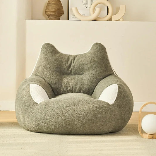 A Premium Teddy Velvet Bean Bag Sofa Cover for Indoor Lounging, in plush light green with cat ear and paw designs, adds a cozy touch to a modern minimalist room with light walls, wood floor, and shelf decor.