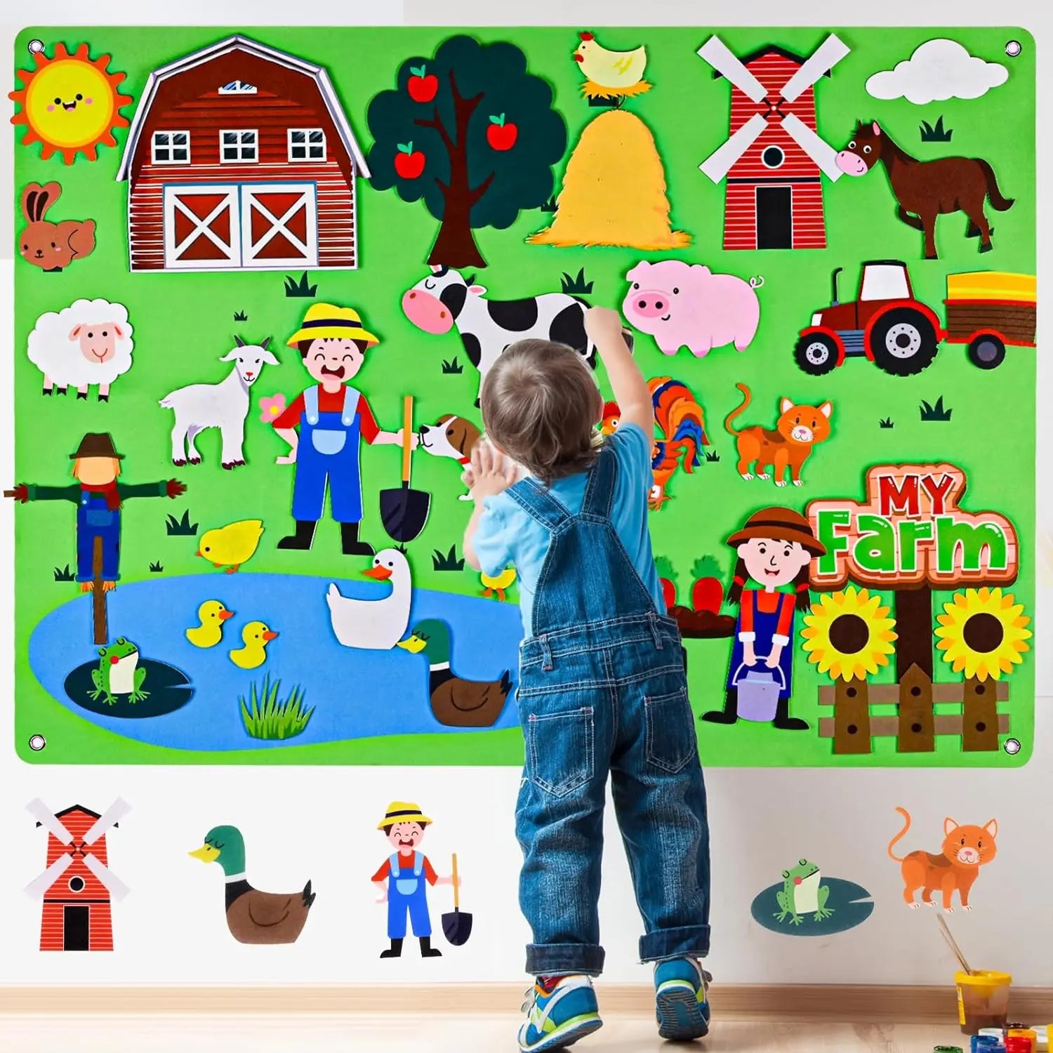 A young child in blue overalls engages with the Farm Animals Felt Story Board Set Interactive Play Kit for Toddlers in color D, featuring a vibrant farm scene with animals, barn, windmill, pond, farmer, tractor, and My Farm sign for early learning fun.