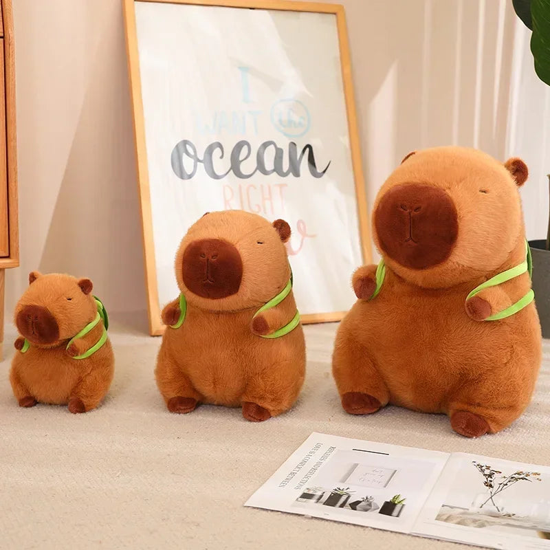 Three Cute Turtle Backpack Capibara Strawberry Hat Capybara Plush Toy stuffed animals sit on a beige carpet with a framed artwork and magazine—perfect as soft dolls, kids toys, birthday gifts, pendants, or decor for plush toy lovers.