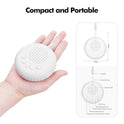 A hand holds the 10 Songs White Noise Sound Machine, a portable baby sleep machine with buttons, lanyard, sound holes, and timer key. Text above: Compact and Portable – perfect for soothing sounds at home or on the go.