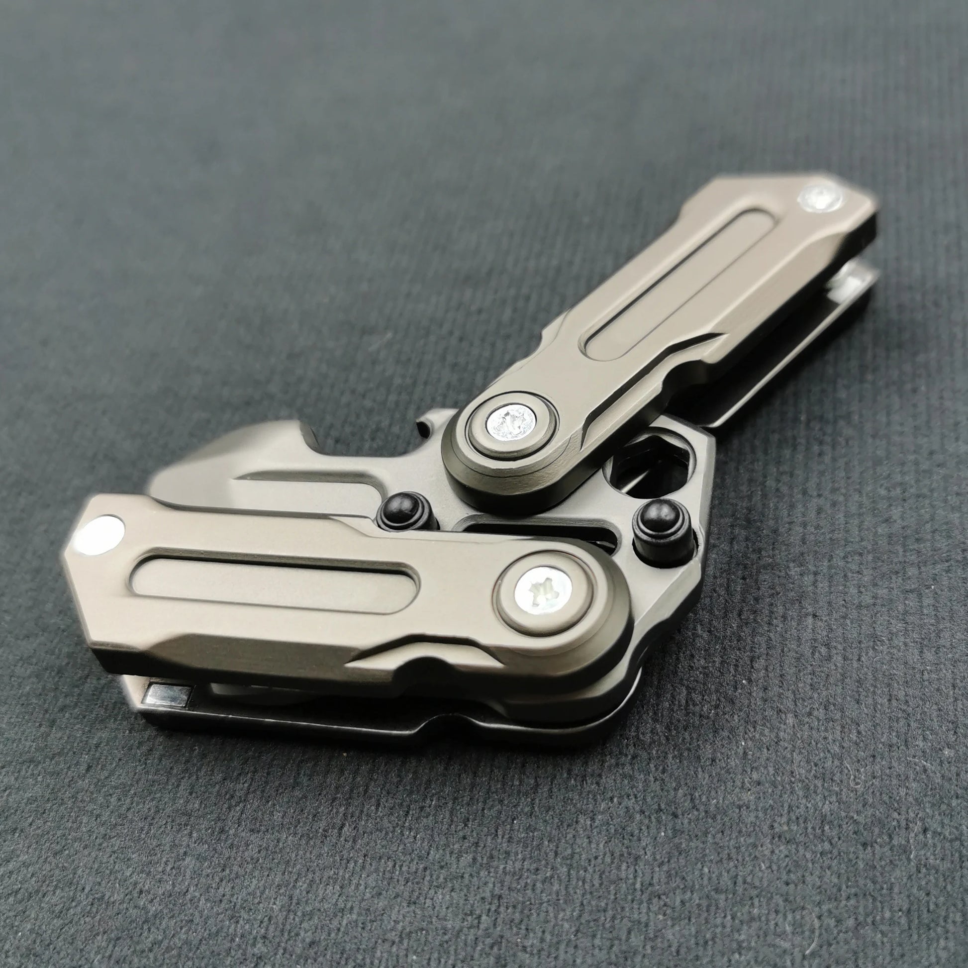 The Fidget Magnetic Coin EDC Adult Decompression Toy, a sturdy multitool with foldable metallic handles and multiple hinges, rests on a gray surface, featuring CE Certification for reliable stress relief and multifunctional use.