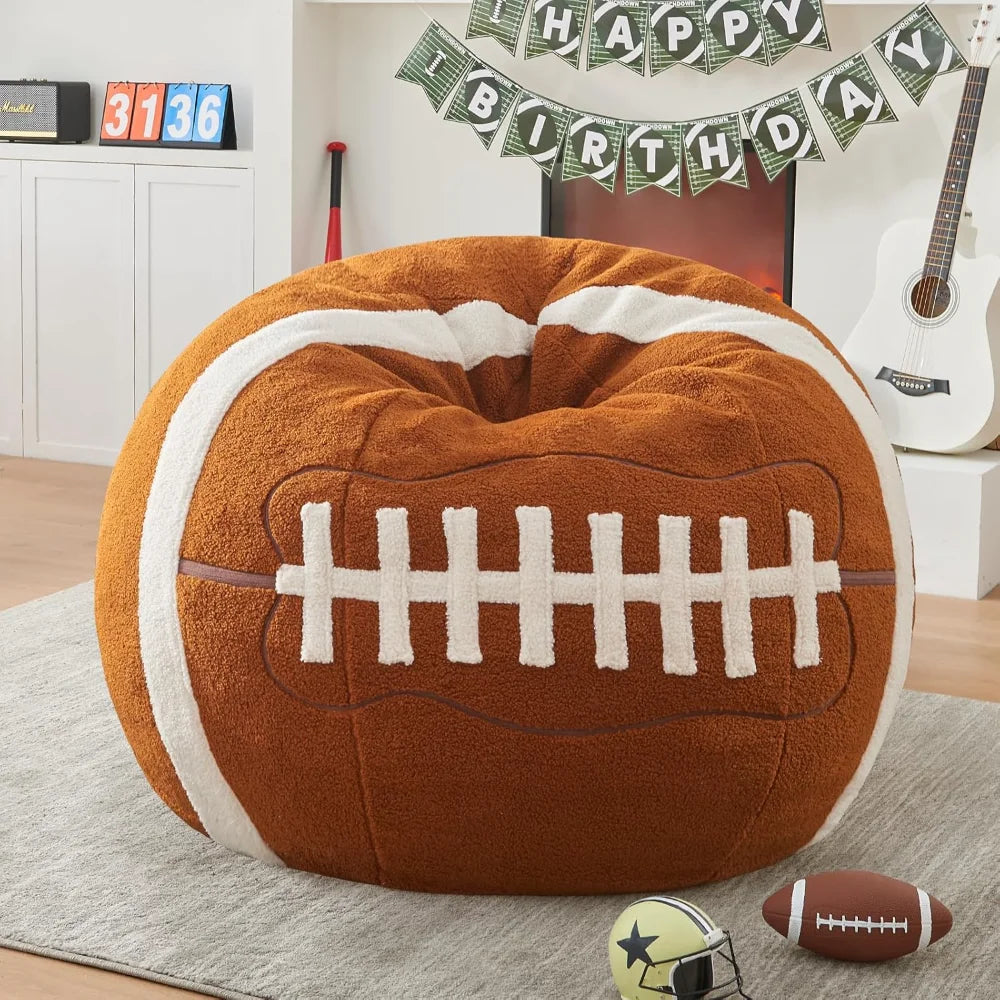 A Sports Football Bean Bag Chair for Adults and Kids sits on a gray rug indoors, with two toy footballs, a guitar, and a Happy Birthday banner above the fireplace—ideal for young sports fans.