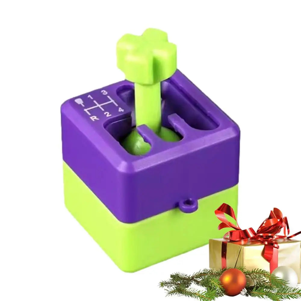 A purple Manual Gear Shifter Keychain 3D Printed Fidget Toy sits beside a decorated Christmas gift, ornaments, and pine branches on a white background. This novelty mood enhancer is chemical-free and made in Mainland China.