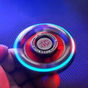 A hand holds the Fidget Spinners for Adults and Kids Stress Relief Anxiety ADHD Toy Metal EDC Hand Spinner with Luminous Light spinning quickly, casting blue and purple light trails against a striped background for stress relief.