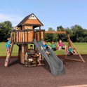 Children enjoy the Playhouse Backyard Discovery Canyon Creek Cedar Swing Set, featuring a slide, swings, climbing wall, and clubhouse. Some swing, one slides, while others climb or play inside the outdoor cedar playground on a sunny day.
