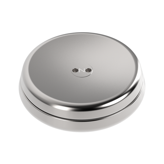 The ONO Slider Steel is a round, metallic silver fidget toy with a smooth surface and two central holes, marked “ON.” Its sleek, minimalistic design is reminiscent of magnetized disks.