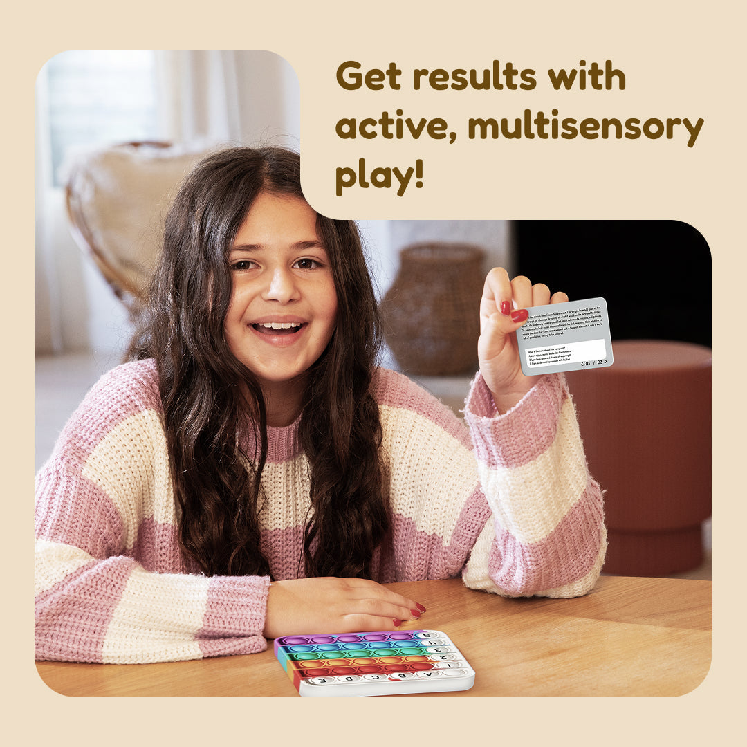 A smiling girl sits at a table with a rainbow-colored letter bubble sensory toy, holding a Super Reader Game Bundle card that reads, Get results with active, multisensory play!.