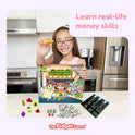 A smiling child plays with the Supermarket Squishy Spree Money Game, featuring a toy cash register tray, miniature fruit-shaped squishies, and play money for counting coins and dollars on a supermarket-themed board.