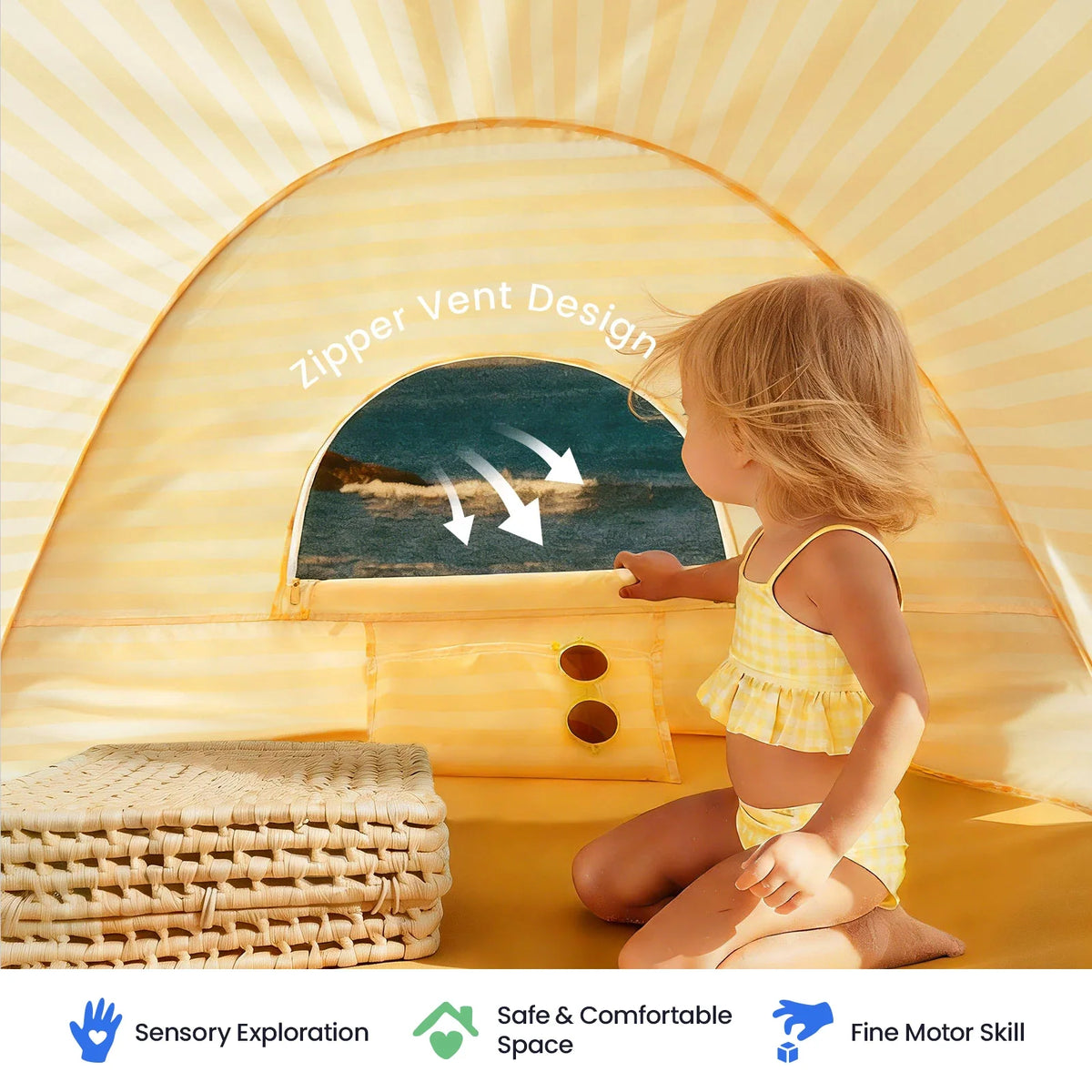 A child sits inside a yellow-striped Kids Beach Tent & Sand Toy Set, opening a zippered window to reveal an ocean view, with icons below for sensory exploration, safe space, and fine motor skills.