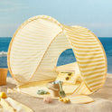 Kids Beach Tent & Sand Toy Set in pastel yellow stripes, set up on sand with a bucket, shovel, and molds inside.