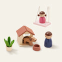 The Tiny Land® Sweetwood Edge Dollhouse set includes a girl on a swing, a dog in a doghouse with bowl, a child figurine, and a potted plant, all displayed on a plain cream background—perfect for contemporary play.