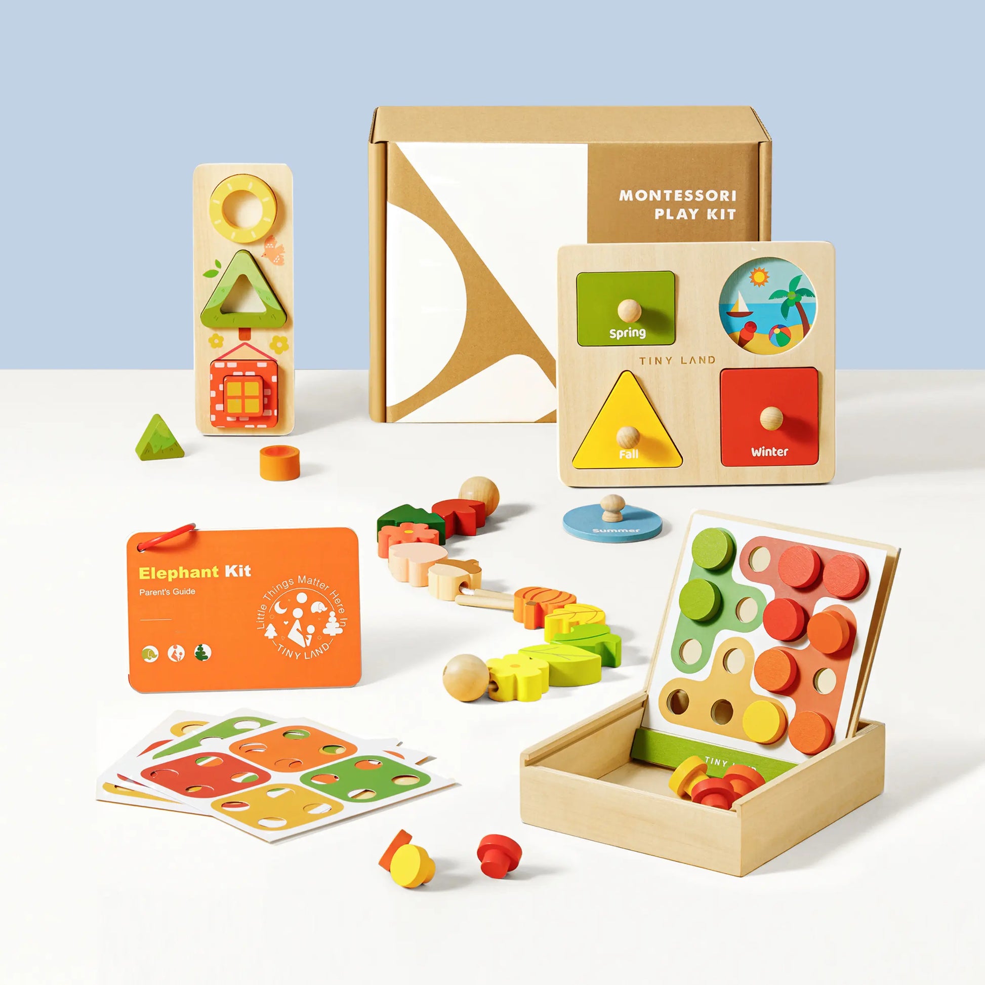 The Tiny Land® Montessori Toys for Toddlers (18–24 Months) kit includes colorful wooden toys, shape sorters, puzzles, stacking blocks, and learning cards—all displayed with its box on a white surface against a light blue background.