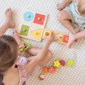 Two children sit on a soft rug, playing with the Tiny Land® Montessori Toys for Toddlers (18–24 Months), a colorful playset with flowers, leaves, and shapes. Their faces are not shown as they enjoy this interactive toy for 2 year olds together.