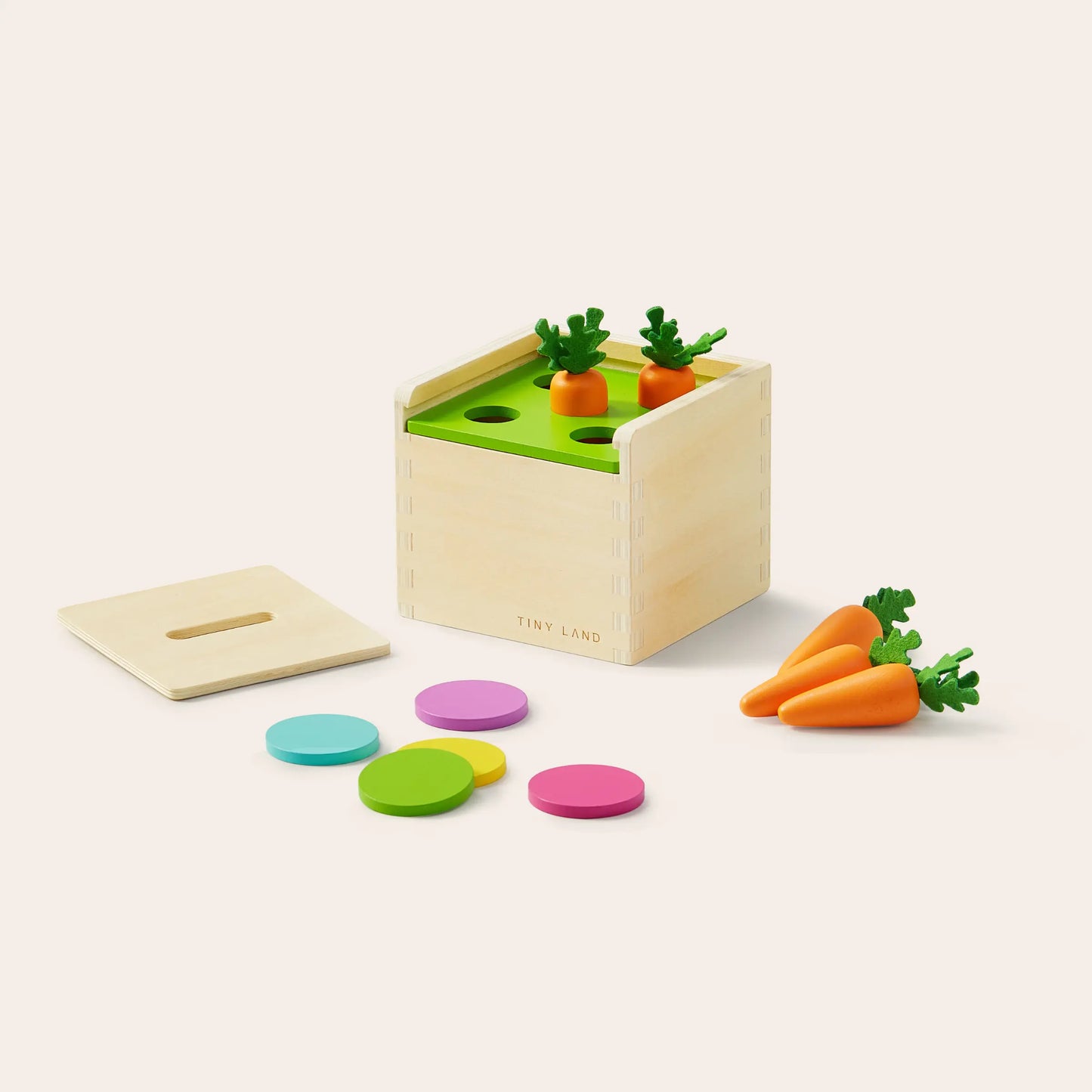 The Tiny Land® Montessori Toys for Toddlers (13–15 Months) is a wooden learning box with a green top for inserting toy carrots, colorful discs, and a removable lid with a slot, making it an ideal hands-on educational toy.