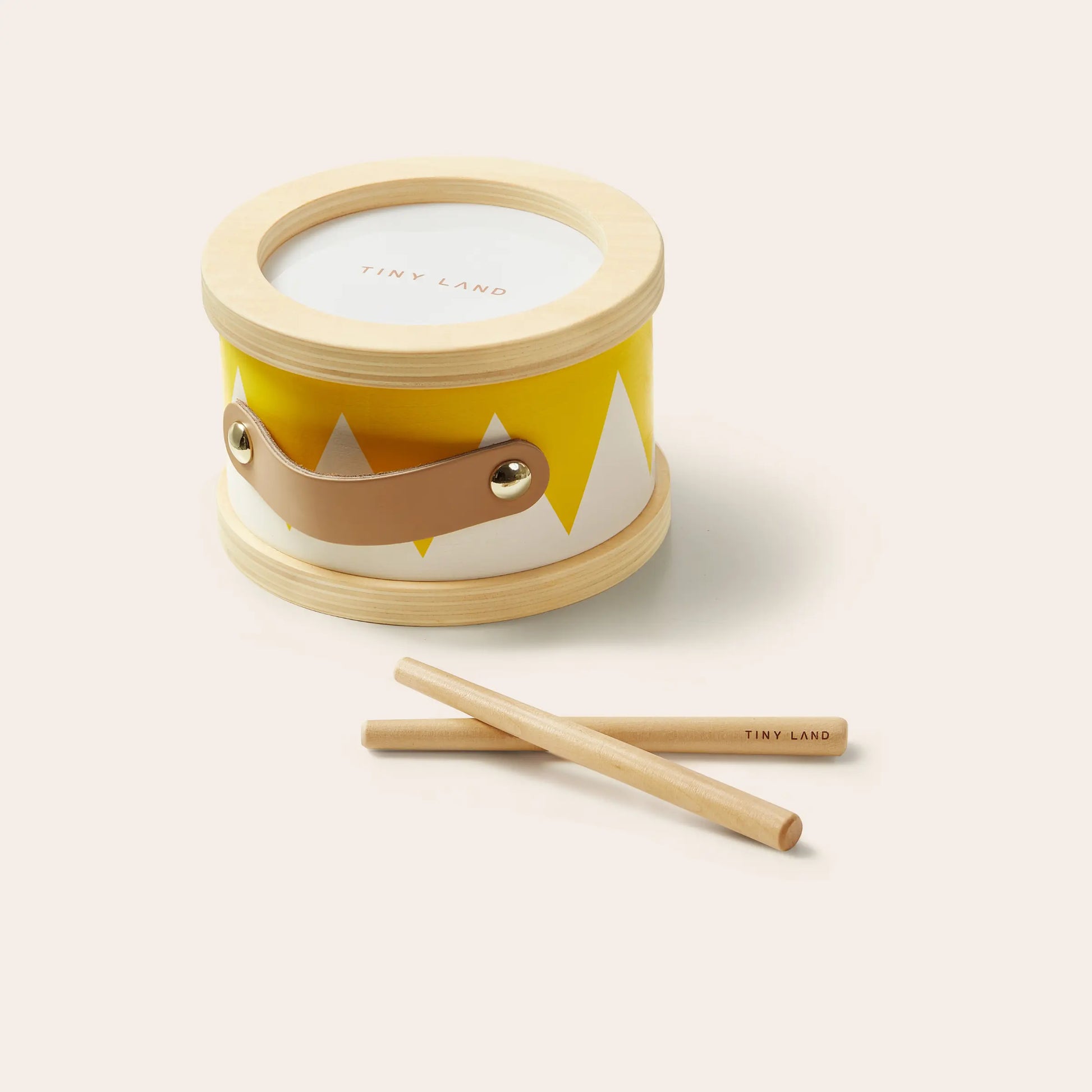 The Tiny Land® Montessori Toys for Toddlers (13–15 Months) features a small toy drum with a yellow and white pattern, wooden rim, brown handle, and includes two wooden drumsticks—perfect as an educational toy.