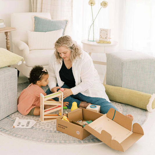 A woman and her 16–18-month-old child sit on a cozy round rug, playing with Tiny Land® Montessori Toys for Toddlers (16–18 Months) – Montessori Educational Toys in a softly lit living room with comfy cushions and neutral decor.