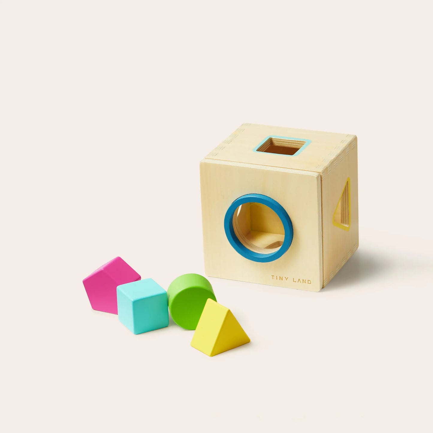 The Tiny Land® Montessori Toys for Toddlers (16–18 Months) is a wooden shape sorter cube with colored openings and four vibrant shapes—pink pentagon, blue cube, green cylinder, yellow triangle—perfect for early learning.