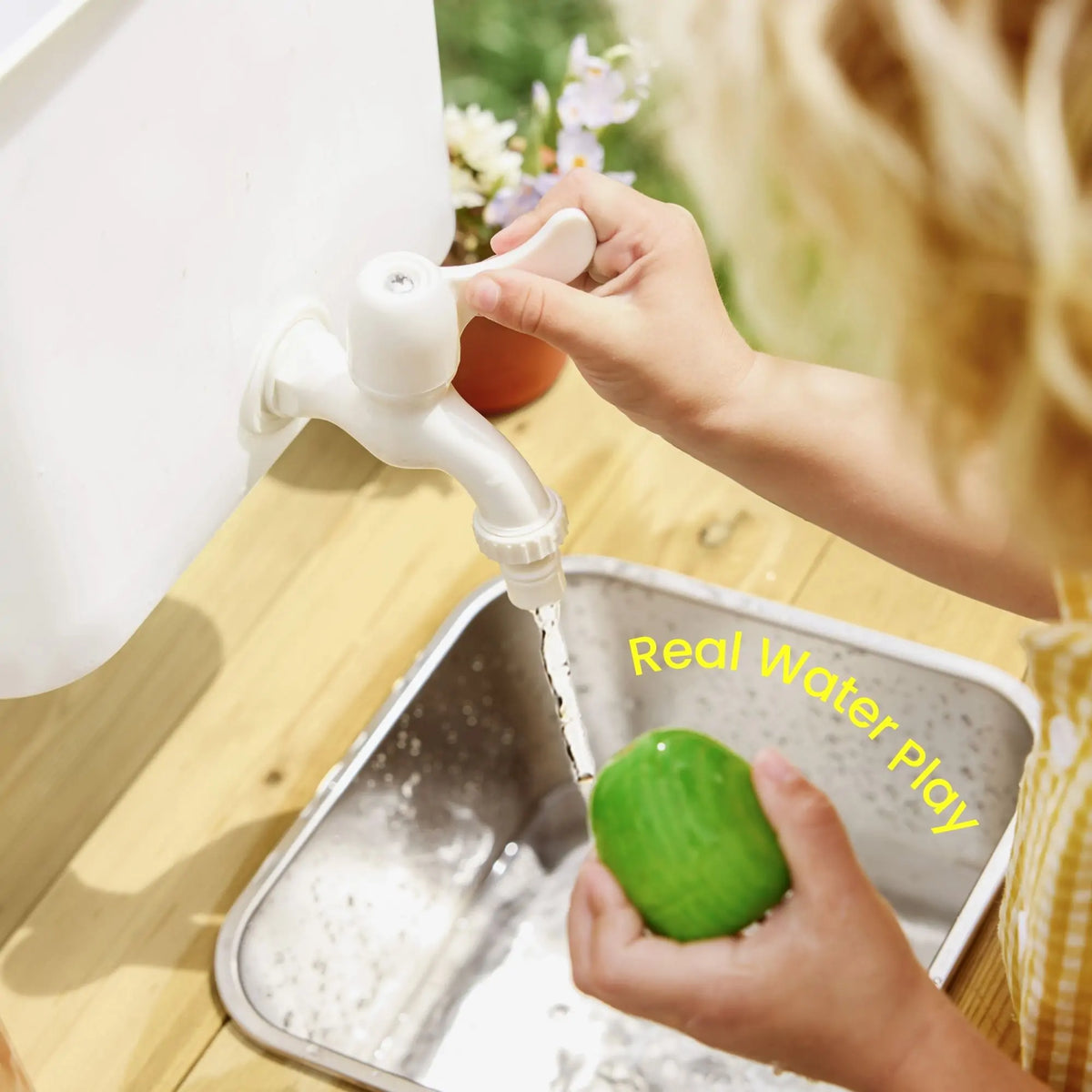 A child’s hands turn a white faucet on a DuoPlay Outdoor Mud Kitchen with Working Faucet, with water flowing from the metal sink onto a green toy, as the text Real Water Play is overlaid on the image.