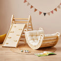 A 7-in-1 Montessori Climbing Set with Play Pad featuring a wooden triangle with a slide and a cushioned rocker resting on a circular rug.