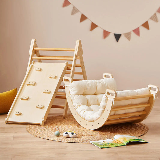 A 7-in-1 Montessori Climbing Set with Play Pad featuring a wooden triangle with a slide and a cushioned rocker resting on a circular rug.