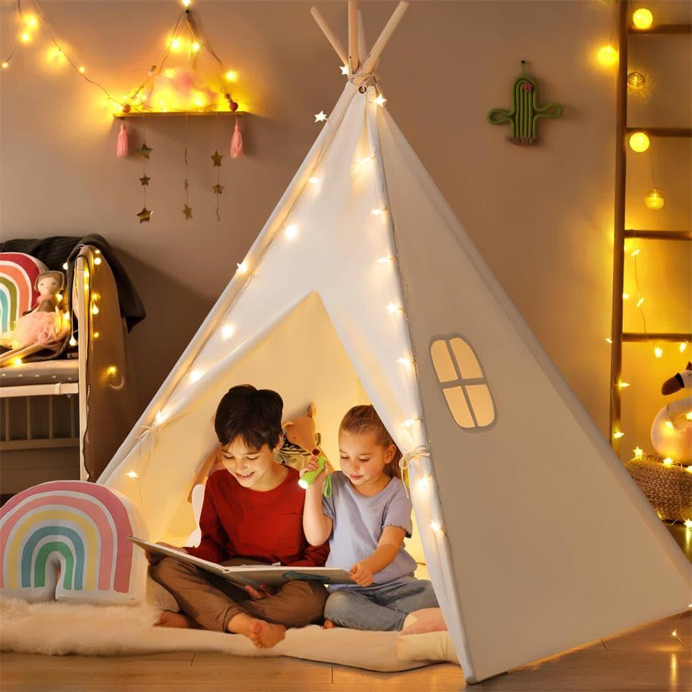 Two children sitting inside a Cozy Kids Teepee Tent with Padded Mat, reading a book while illuminated by string lights.
