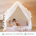 A child sits inside a Large Cozy Cabin Play Tent with Star Lights, which is draped with sheer fabric to create a cozy reading nook.
