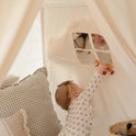 A baby reaches through a window in a Large Cozy Cabin Play Tent with Star Lights to hand a wooden fox toy to an adult peering in.