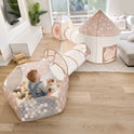 A small child plays in a Tiny Land® Discovery 5-in-1 Play Tunnel With no Balls in a bright, modern living room with wooden floors and a large window.