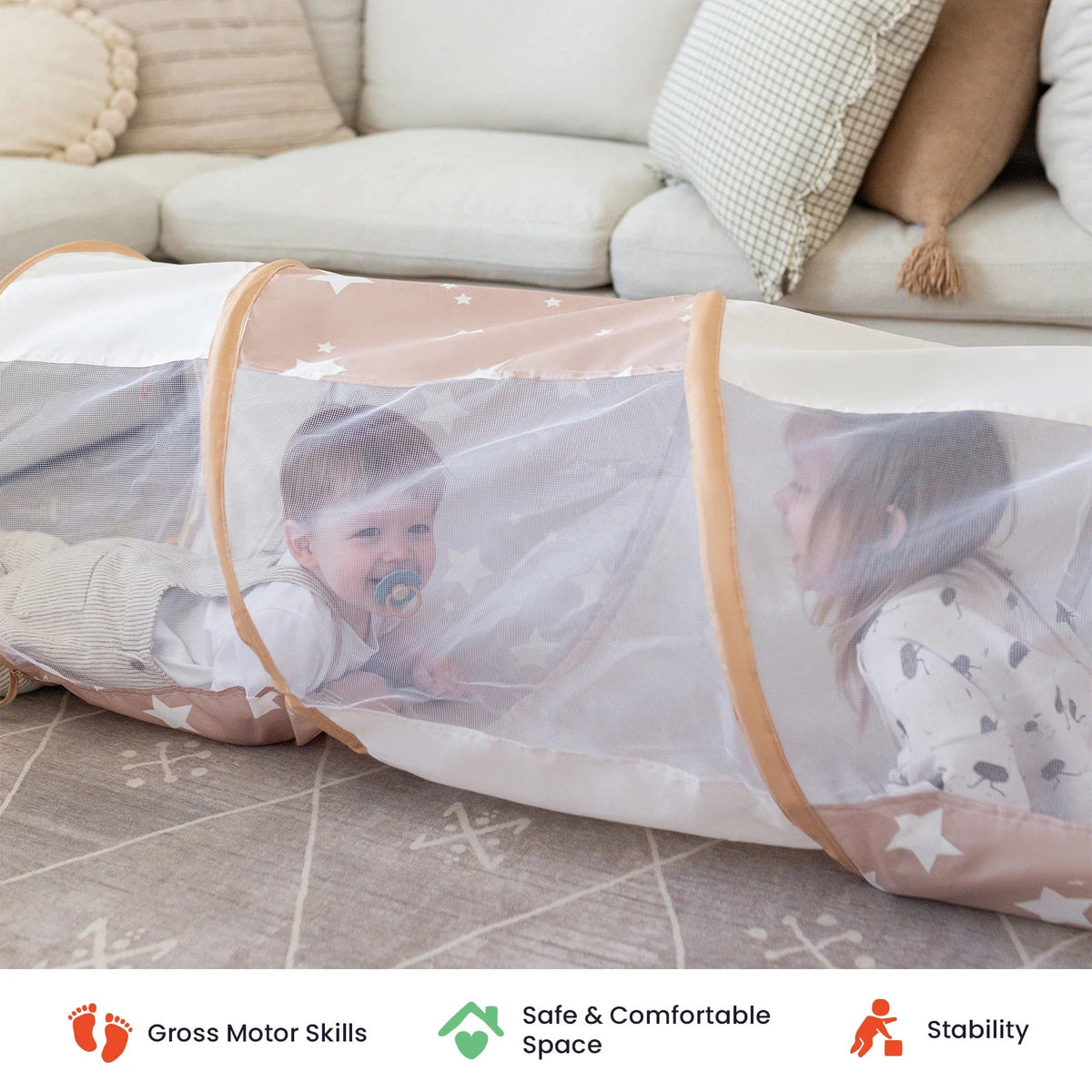 Two children crawl inside a long, star-patterned mesh Adventure Crawl Tunnel (68″) on a living room rug.