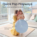 A woman kisses a smiling girl while holding a collapsed, light blue storage bag for an Adventure Crawl Tunnel (68″) in a living room, with text overlaid reading Quick Pop Playways and Comes with the carry bag.