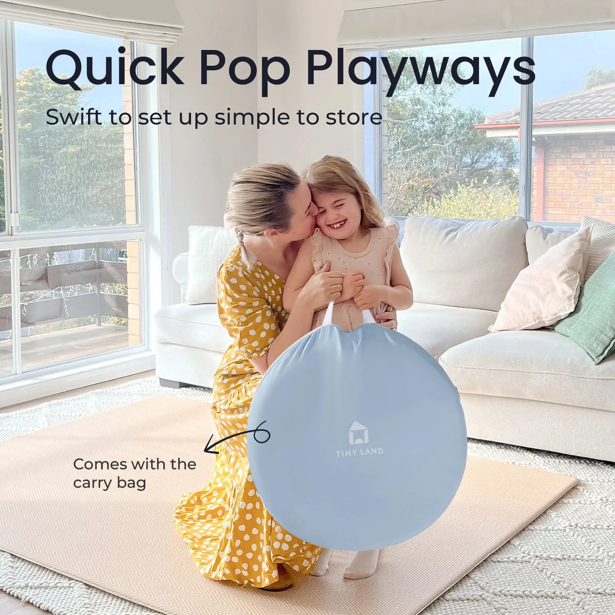 A woman kisses a smiling girl while holding a collapsed, light blue storage bag for an Adventure Crawl Tunnel (68″) in a living room, with text overlaid reading Quick Pop Playways and Comes with the carry bag.