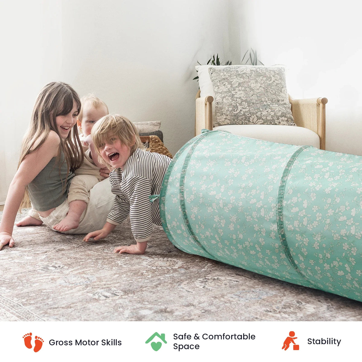 Three children play near a long, floral-patterned Adventure Crawl Tunnel (68″) on the floor.