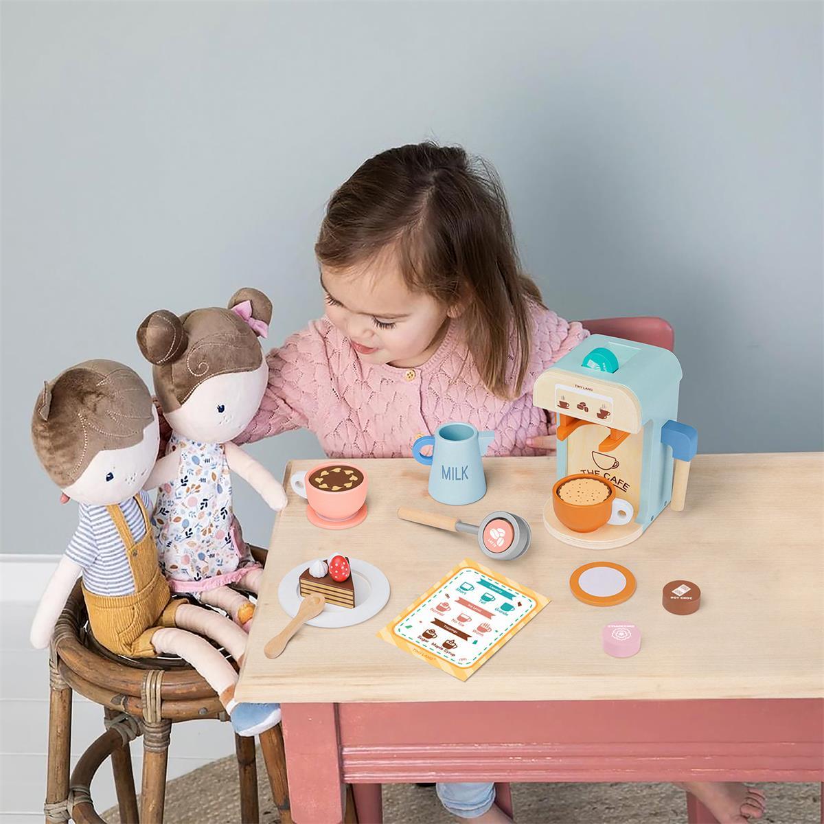 A young girl plays with a Wooden Play Coffee Maker Set, serving two plush dolls at a small table with toy coffee, milk, and a slice of cake during a kids role play toy session.