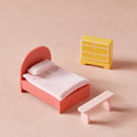 The Tiny Land® Sweetwood Love Dollhouse without Dolls includes a pink bed with pillow, matching bench, and a small yellow dresser—ideal for imaginative play in any wooden dollhouse for girls.