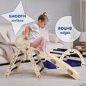 A young child plays on the Apollo 4in1 Climbing Set: Pikler Triangle, Arch, Slide Board, and Cushion for Little Toddlers Astronauts (1–3 Years), a Montessori climbing set with space-themed designs. Text highlights the smooth surface and round edges of these toddler climbing toys. A beige couch and a rug are in the background.