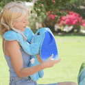 A woman holds a Bo the Moon Pal – 5 lb Weighted Plush, an ultra-soft, jumbo weighted toy with large ears and cartoonish eyes.