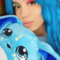A person with bright blue hair holding a Bo the Moon Pal – 5 lb Weighted Plush, an ultra-soft jumbo weighted plush with large eyes and long ears.