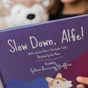 A child holds the Slow Down, Alfie! – Picture Book, which features an illustration of a corgi on its cover.