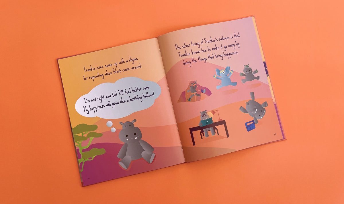 An open Frankie & Gloob – Picture Book showing a gray hippopotamus sitting on the left, with illustrations of the hippo dancing, working, and playing music on the right, accompanied by text.