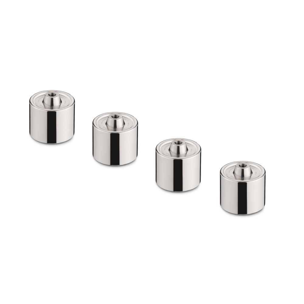 The Hexcal Studio Extension Kit features four shiny, cylindrical metal weights with central top indentations and subtle height differences, arranged in a row—perfect for achieving optimal monitor positioning in your ergonomic desk setup.