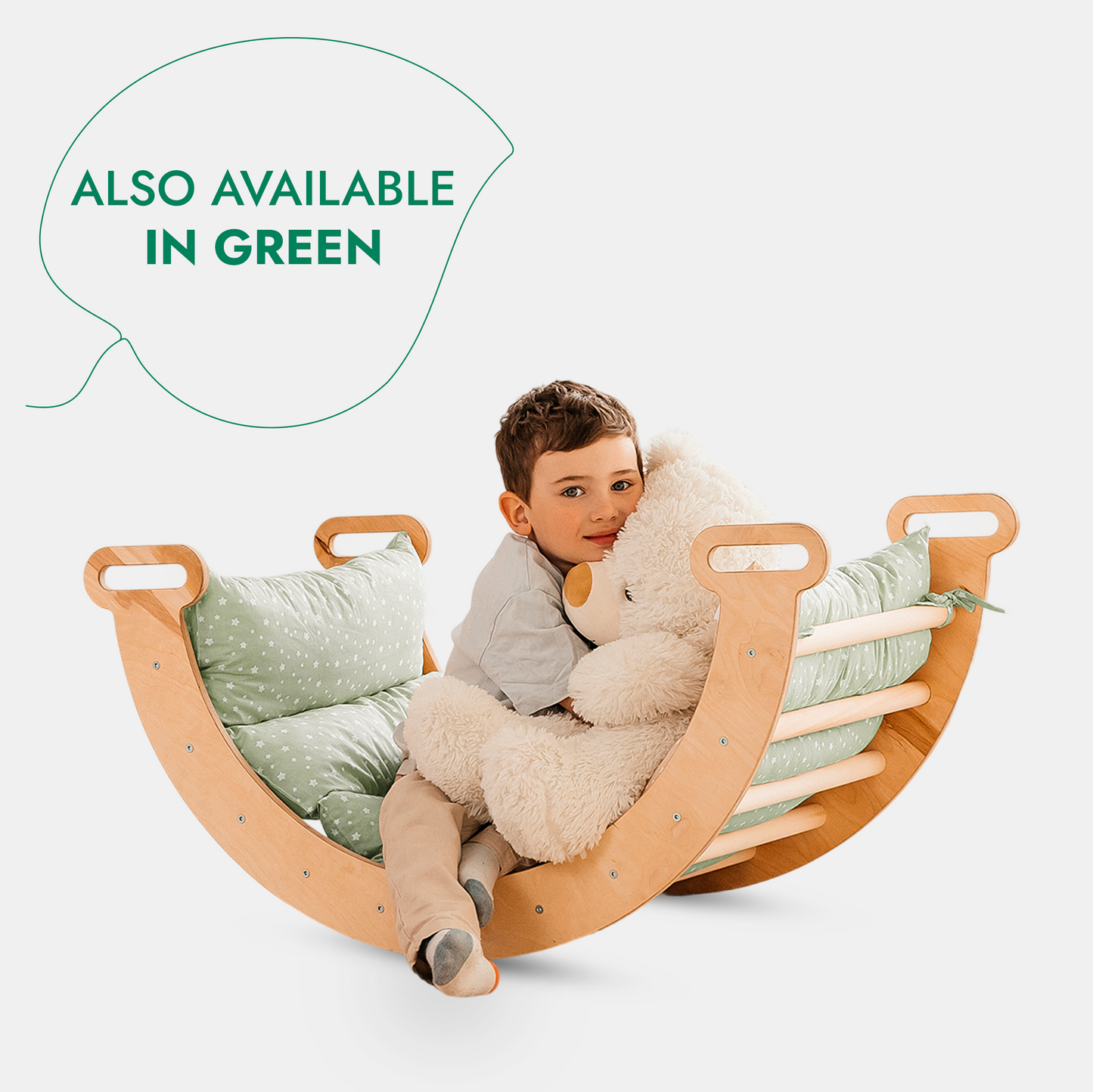 A young child hugs a large white teddy bear while sitting in a wooden rocking toy with green cushions, part of the 5in1 Montessori Climbing Set (Triangle Ladder + Arch/Rocker + Slide Board/Ramp + Netting rope + Cushion). Text reads, ALSO AVAILABLE IN GREEN.