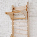 Upgrade your workout setup with the Gym Addition to the Climbing Ladders—this wooden wall-mounted gym ladder features horizontal bars and an upper pull-up bar, securely attached to a white brick wall for versatile indoor use. Enhance functionality and fun by pairing it with a triangle ladder or other Swedish ladder add-ons.