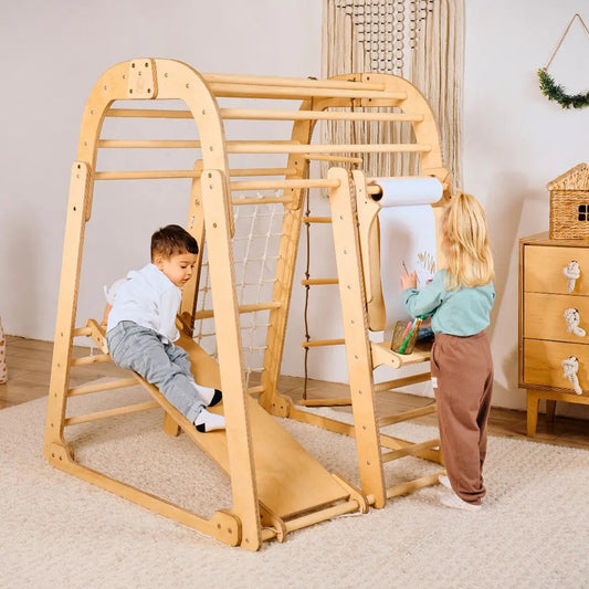 Two young children enjoy the Indoor Playground for Children—one climbs the 7in1 playground’s slide while the other creates at the art set. With swings and a stylish, neutral design, this indoor playset is both inviting and functional.