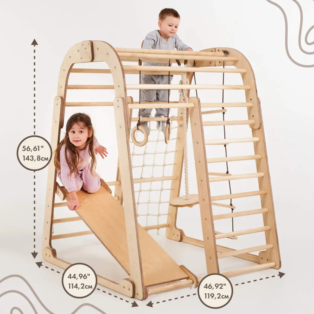 Two young children play on the Indoor Wooden Playground for Children - 6in1 Playground + Swings Set + Slide Board, a Montessori-inspired wooden climbing structure with a slide. This kids playground features clearly marked dimensions—height: 56.61 in (143.8 cm), width: 44.96 in (114.2 cm), and length: 46.92 in (119.2 cm)—making it an ideal indoor playset for active little ones.